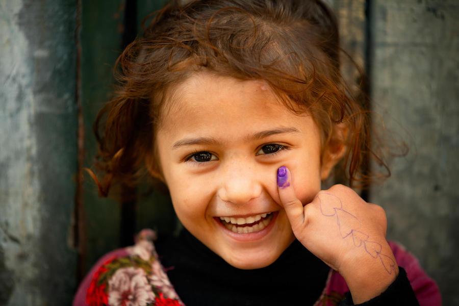 In Lahore, Pakistan, a 4-year old-girl smiles for the UNICEF camera showing her marked finger after receiving the polio vaccine.