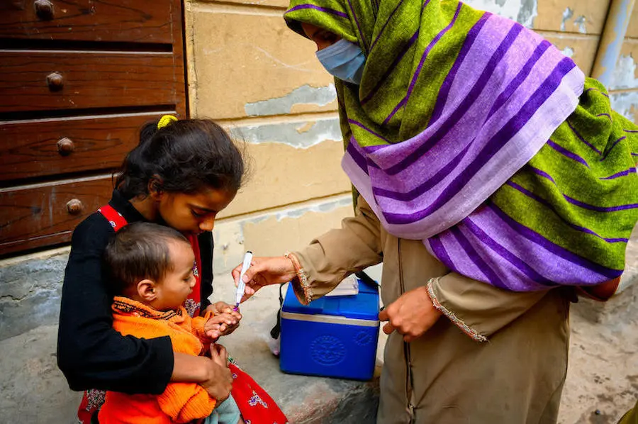 A UNICEF-trained vaccinator in Pakistan inks a child's finger to show he is now safe from polio. A UNICEF-trained vaccinator in Pakistan inks a child's finger to show he is now safe from polio.