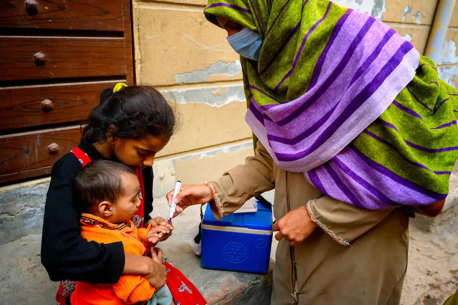 In January 2021, Shumaila, a polio vaccinator in Lahore, Pakistan, marks the finger of an 18-month old boy with the help of his sister, to show that he has received his vaccination. In January 2021, Shumaila, a polio vaccinator in Lahore, Pakistan, marks the finger of an 18-month old boy with the help of his sister, to show that he has received his vaccination.