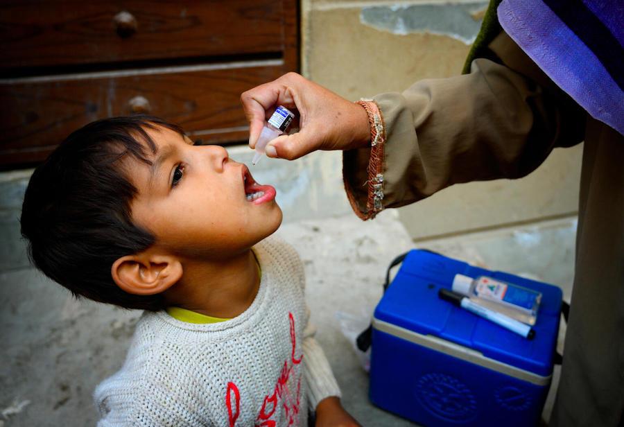 A 5-year-old boy receives the polio vaccine from Shumaila, a UNICEF-supported polio vaccinator in Lahore, Pakistan on January 11, 2021. 