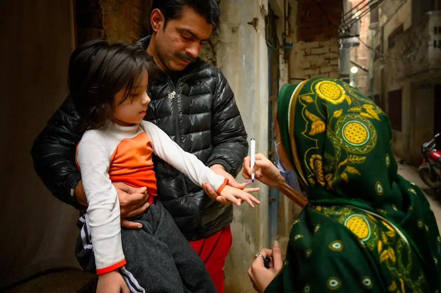In January 2021, Sumaira, a polio vaccinator in Lahore, Pakistan, marks the finger of a 4-year-old with the help of the girl's father after vaccinating her with polio and giving her Vitamin A supplementation. In January 2021, Sumaira, a polio vaccinator in Lahore, Pakistan, marks the finger of a 4-year-old with the help of the girl's father after vaccinating her with polio and giving her Vitamin A supplementation.
