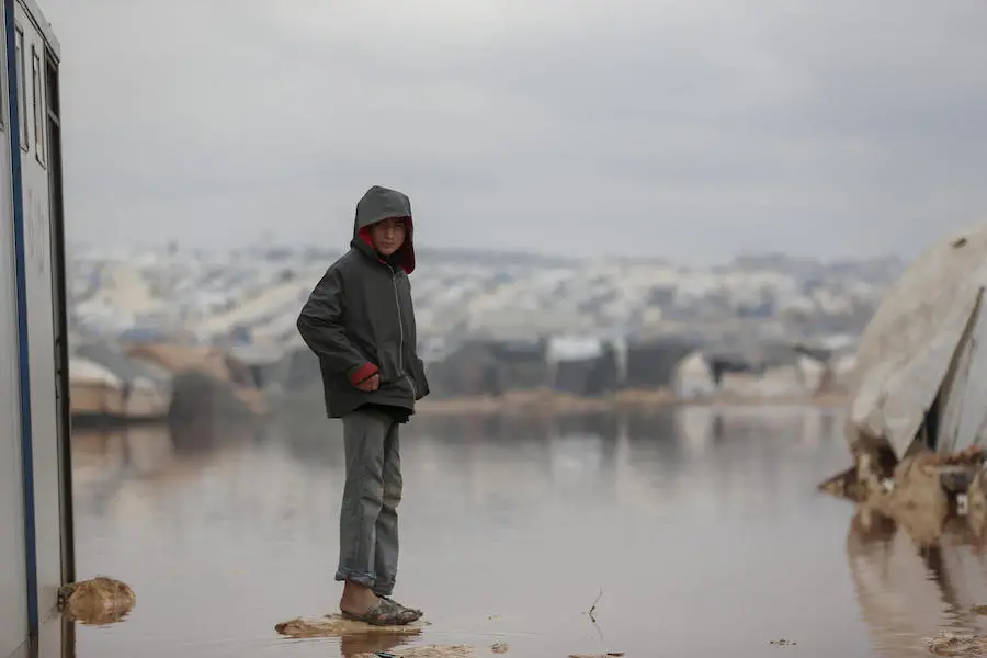 On 19 January 2021, a child stands on a dry patch surrounded by floodwater in Kafr Losin Camp in northwest Syrian Arab Republic. On 19 January 2021, a child stands on a dry patch surrounded by floodwater in Kafr Losin Camp in northwest Syrian Arab Republic.
