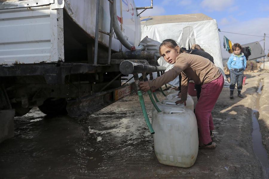 On 19 January 2021, a child collects water from a tanker truck in Kafr Losin Camp in northwest Syrian Arab Republic. UNICEF is working with partners to provide families with basic services.