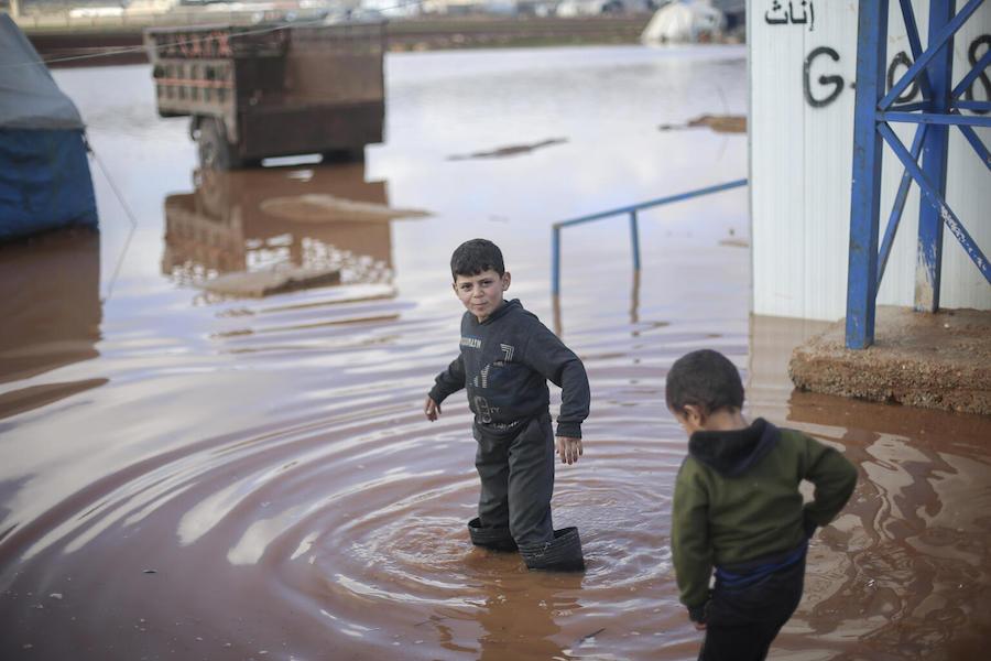 On 19 January 2021, children walk through a flooded area of Kafr Losin Camp in northwest Syrian Arab Republic.
