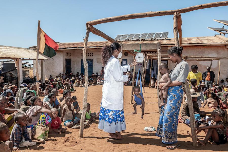Children are weighed by a health worker outside a facility in Maroalopoty where UNICEF supports malnutrition screenings and treatment, including the distribution of therapeutic food.