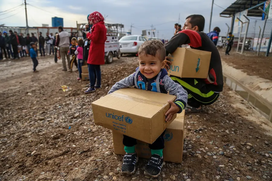 A young Syrian refugee staying at a camp in East Lebanon receives a box of warm winter clothing provided by UNICEF.