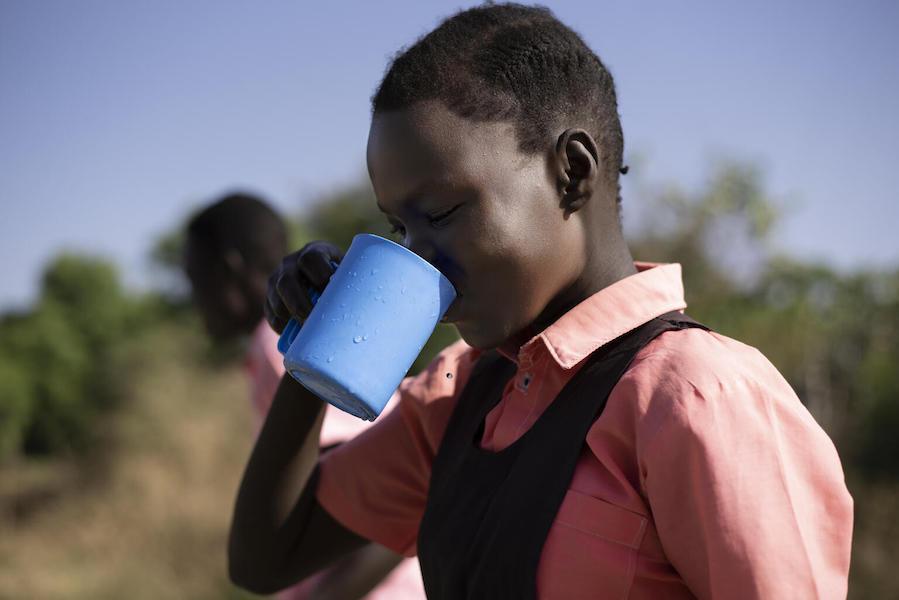 Keziah, 14, drinks water from the borehole at AIC Nursery and Primary School in Torit, South Sudan in February 2021.