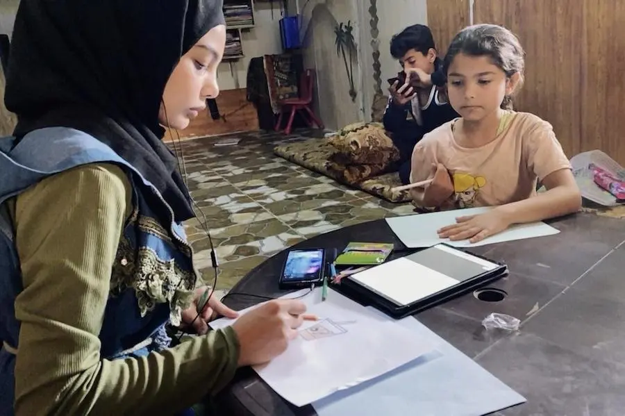 At home in the Za'atari Refugee Camp in Jordan, Hala, 15, a Syrian refugee, and her sister watch a video on painting techniques using a UNICEF-supported blended learning program designed to close learning gaps. At home in the Za'atari Refugee Camp in Jordan, Hala, 15, a Syrian refugee, and her sister watch a video on painting techniques using a UNICEF-supported blended learning program designed to close learning gaps.