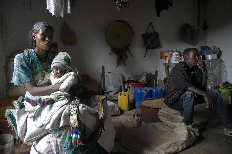 Woman Holding Baby Next to Man in their Home