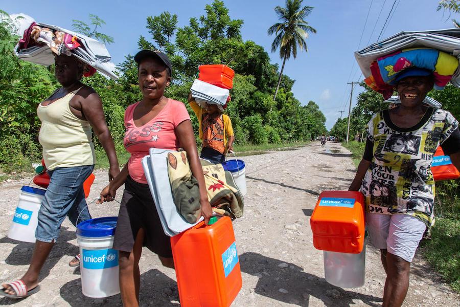 On August 18, 2121, just days after Haiti’s powerful earthquake, people carry emergency supplies distributed by UNICEF in Valere, a village in Hait’s Sud Department.