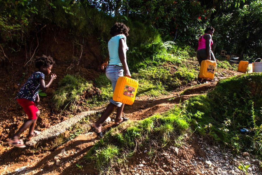 On August 18 2021, in Marceline, near Haiti's Camp Perrin district, people carry jerry cans of water from one of the four water stations supported by UNICEF in Les Cayes.