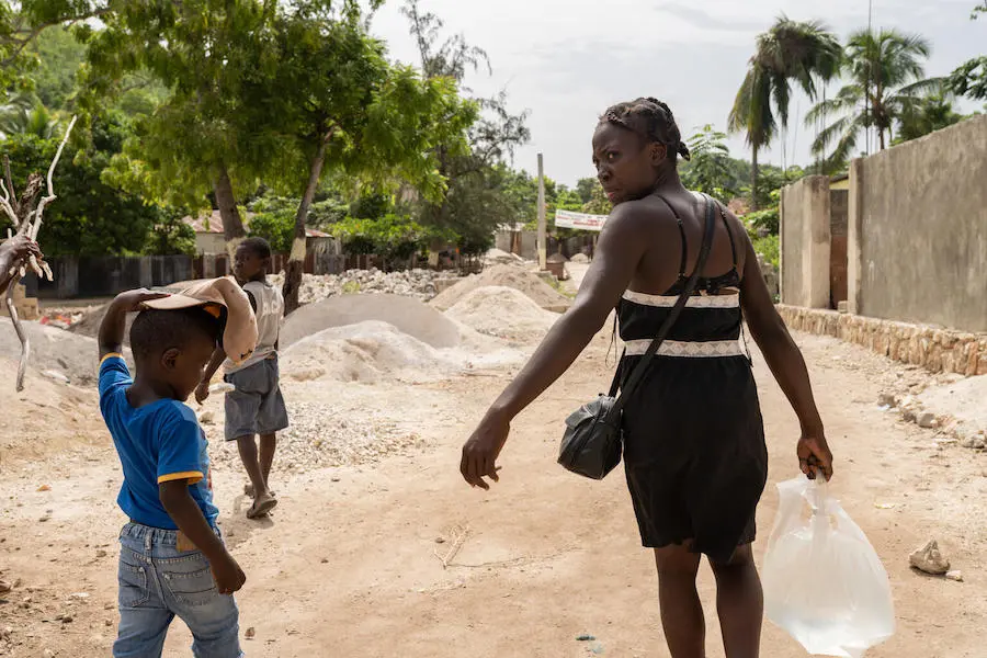 Woman Carrying Water Next to Child