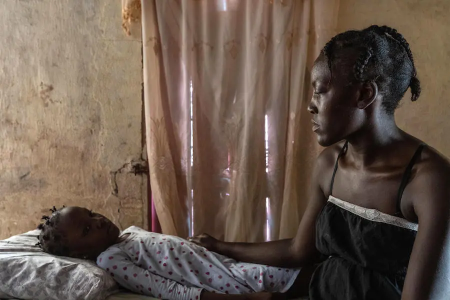 Woman Looking at Child Laying in Bed