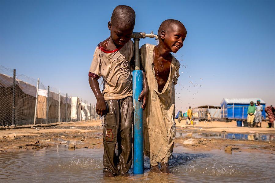 Children play under a water tap during a recess at a UNICEF supported primary school inside Bukasi Internally Displaced People&#039;s camp, in Maiduguri, Borno State, Nigeria