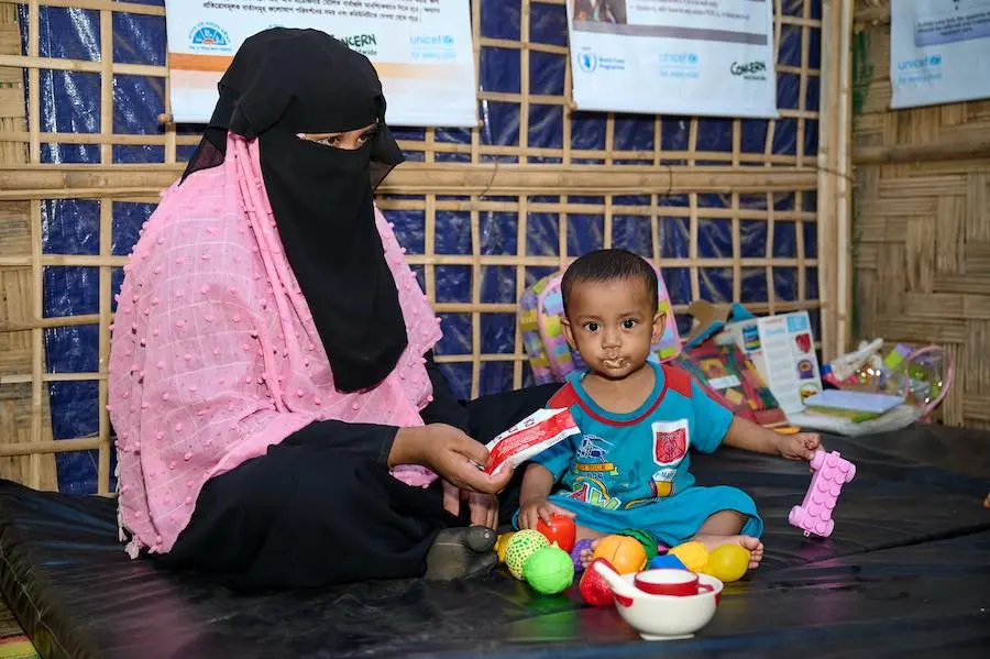 A Rohingya refugee who lives in Bangladesh gives her malnourished 10-month-old baby Plumpy Nut therapeutic food at a UNICEF Nutrition Center. A Rohingya refugee who lives in Bangladesh gives her malnourished 10-month-old baby Plumpy Nut therapeutic food at a UNICEF Nutrition Center.