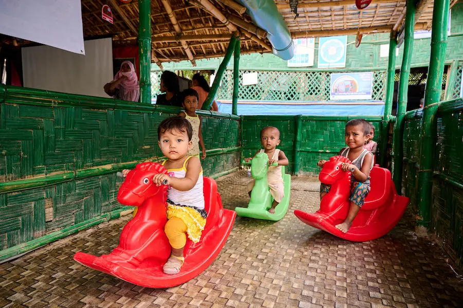 Young children play in the waiting area of a UNICEF-supported integrated nutrition facility, a dedicated space for children to play in Rohingya refugee Camp-15, Jamtoli, Cox's Bazar, Bangladesh. Young children play in the waiting area of a UNICEF-supported integrated nutrition facility, a dedicated space for children to play in Rohingya refugee Camp-15, Jamtoli, Cox's Bazar, Bangladesh.