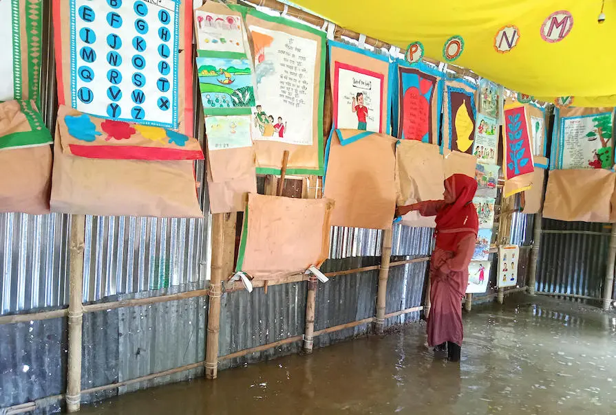 Saleha Begum, an organizer at a UNICEF-supported school, checks the state of the learning materials in the flooded school in Sunamganj, Bangladesh on May 17, 2022. Saleha Begum, an organizer at a UNICEF-supported school, checks the state of the learning materials in the flooded school in Sunamganj, Bangladesh on May 17, 2022.