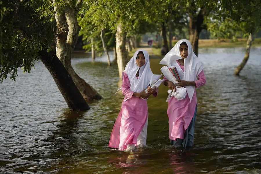 Girls wade through floodwaters on the way to school in Sunamganj, Bangladesh on May 23, 2022.. Girls wade through floodwaters on the way to school in Sunamganj, Bangladesh on May 23, 2022..