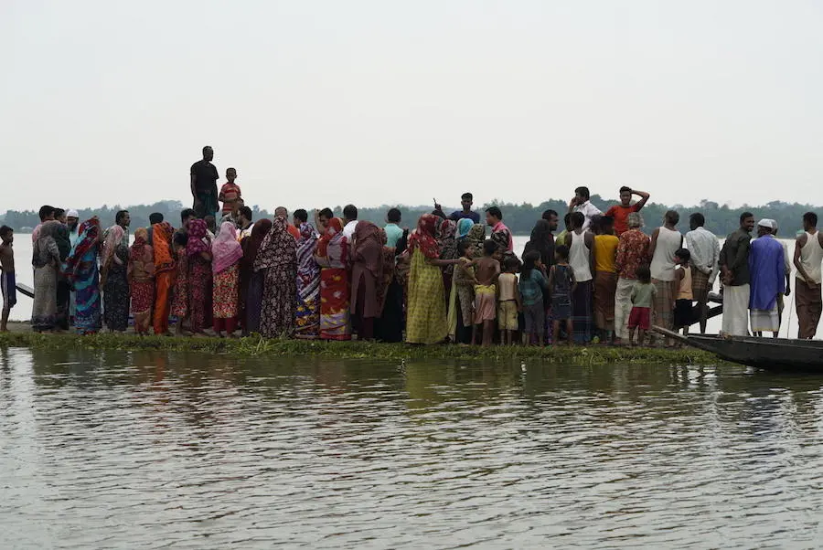 Families crowd onto a dry strip of road as they flee their flooded homes in Sunamganj, Bangladesh on May 23, 2022. Families crowd onto a dry strip of road as they flee their flooded homes in Sunamganj, Bangladesh on May 23, 2022.