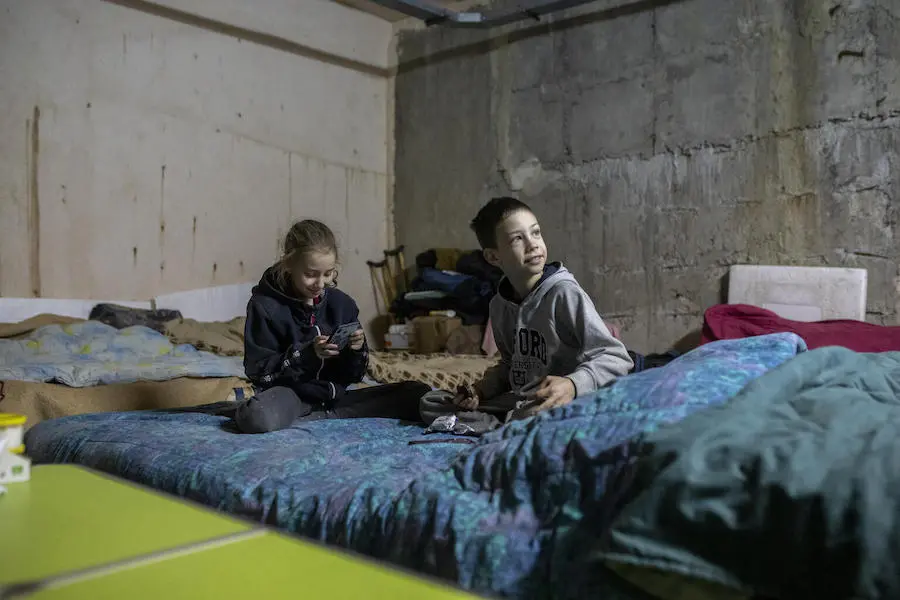 Alina and Artem, both 9, play with a phone in an underground car park now serving as a bomb shelter in the city of Kharkiv, northeastern Ukraine. Alina and Artem, both 9, play with a phone in an underground car park that is now serving as a bomb shelter in the city of Kharkiv, northeastern Ukraine.