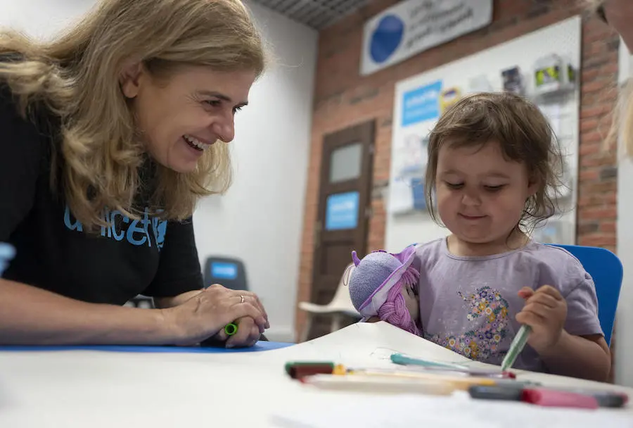 Paloma Escudero, UNICEF Director of Global Communication and Advocacy, sits with a child as she draws, while visiting the Blue Dot center for refugees from Ukraine at the train station in Krakow, Poland, on June 3, 2022. Paloma Escudero, UNICEF Director of Global Communication and Advocacy, sits with a child as she draws, while visiting the Blue Dot center for refugees from Ukraine at the train station in Krakow, Poland, on June 3, 2022.