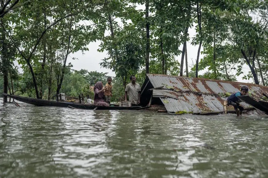 In northeastern Bangladesh, a family leaves their home, submerged by major flooding in June 2022. In northeastern Bangladesh, a family leaves their home, submerged by major flooding in June 2022.