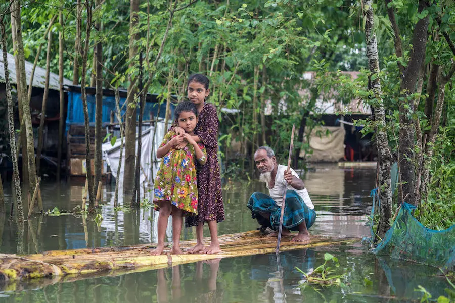 Two Girls on Makeshift Raft with Man Rowing