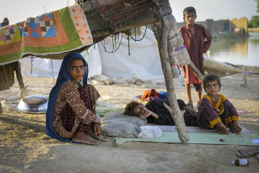 Children take refuge beneath a charpai after fleeing flooding in Jacobabad district, Sindh Province, Pakistan, on Sept. 10, 2022. Children in flood-stricken Jacobabad district, Sindh Province, Pakistan, on Sept. 10, 2022.