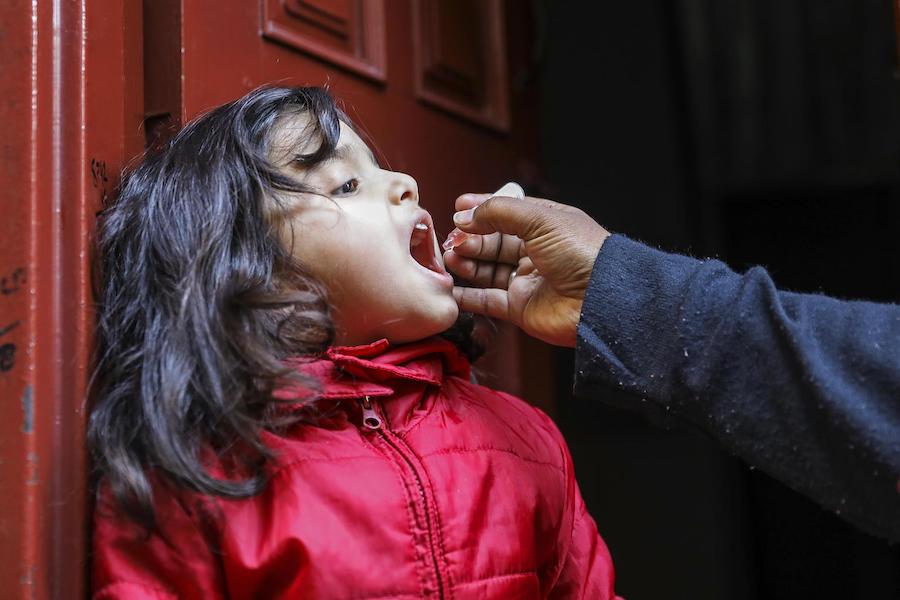 UNICEF-supported vaccinator Shaima Shahid vaccinates Aneesa, 4, against polio at her front door in the Bhatti gate area of Lahore Punjab Province, Pakistan in January 2019.