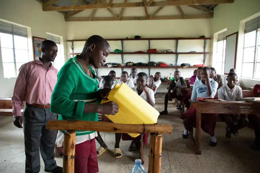 A UNICEF-trained health worker demonstrates how to make and use a tippy tap handwashing device at the Damasiko Primary School in western Uganda's Kamwenge district in 2019. A UNICEF-trained health worker demonstrates how to make and use a tippy tap handwashing device at the Damasiko Primary School in western Uganda's Kamwenge district in 2019.