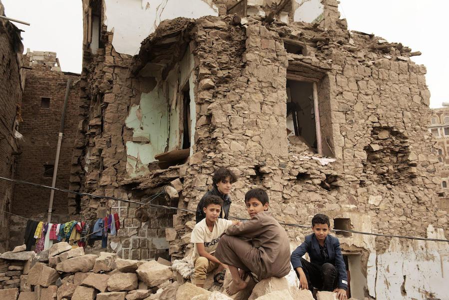 Children sit in front of a house damaged by an air strike inside the old city of Sana'a, Yemen on July 20, 2019.