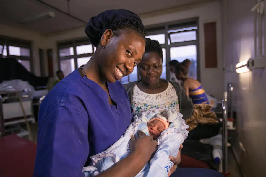 In Uganda, UNICEF-supported midwife Uwingabire Mary joyfully holds the firstborn baby of Kabugho Moureen, 23. In Uganda, UNICEF-supported midwife Uwingabire Mary joyfully holds the firstborn baby of Kabugho Moureen, 23.