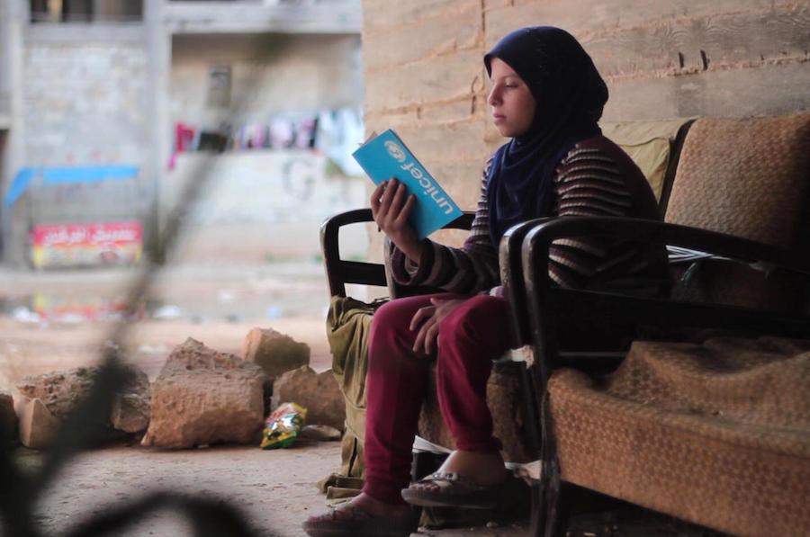 In Aleppo, Syria in 2016, 12-year-old Saja reads from a UNICEF notebook. She lost her leg in a bombing attack on her neighborhood, but is back in school and hoping to compete in the Special Olympics one day.