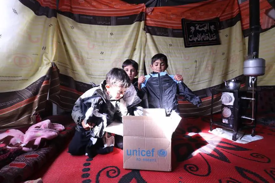 Children peruse the contents of a box full of UNICEF-supported winter supplies in the industrial zone of Hassia in rural Homs in the Syrian Arab Republic on on 7 December 2019. Children peruse the contents of a box full of UNICEF-supported winter supplies in the industrial zone of Hassia in rural Homs in the Syrian Arab Republic on on 7 December 2019.