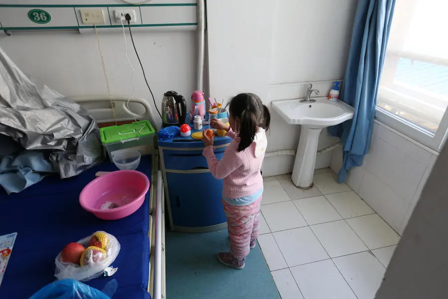 Five-year-old Yuanyuan peels an orange in a ward, where she now lives, in a hospital affiliated with Wuhan University of Science and Technology in China in February 2020.