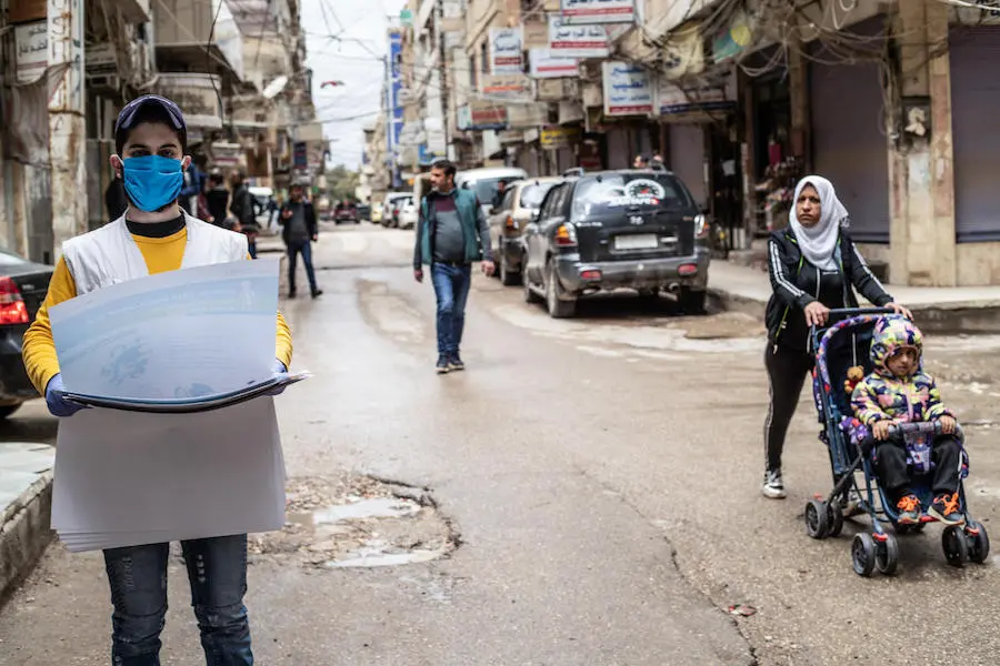 On April 1, 2020, a UNICEF volunteer hangs posters providing important instructions on how to protect against COVID-19 in Qamishly, a city of some 250,000 in northeast Syrian Arab Republic. On April 1, 2020, a UNICEF volunteer hangs posters providing important instructions on how to protect against COVID-19 in Qamishly, a city of some 250,000 in northeast Syrian Arab Republic. 