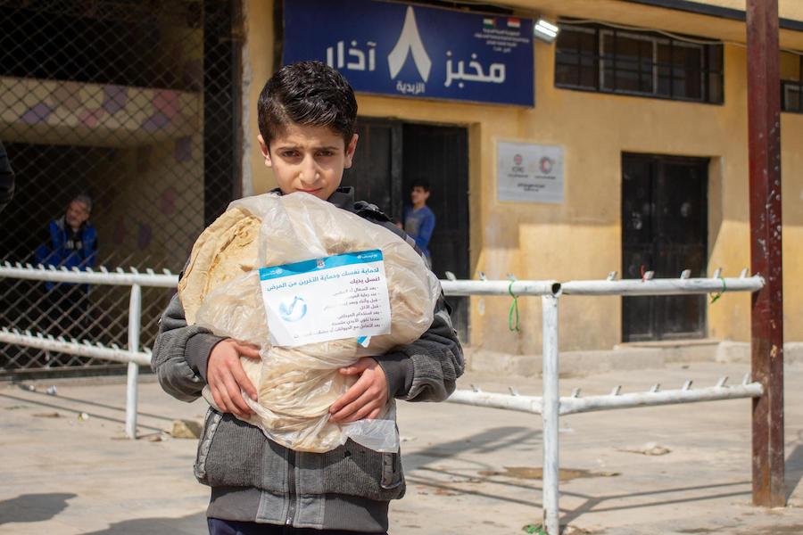On April 2, 2020, Mohammad, 11, holds a bread bag with a UNICEF label containing messages raising awareness on issues around the 2019 novel coronavirus, in the al-Zebdieh neighborhood of Aleppo, Syrian Arab Republic.