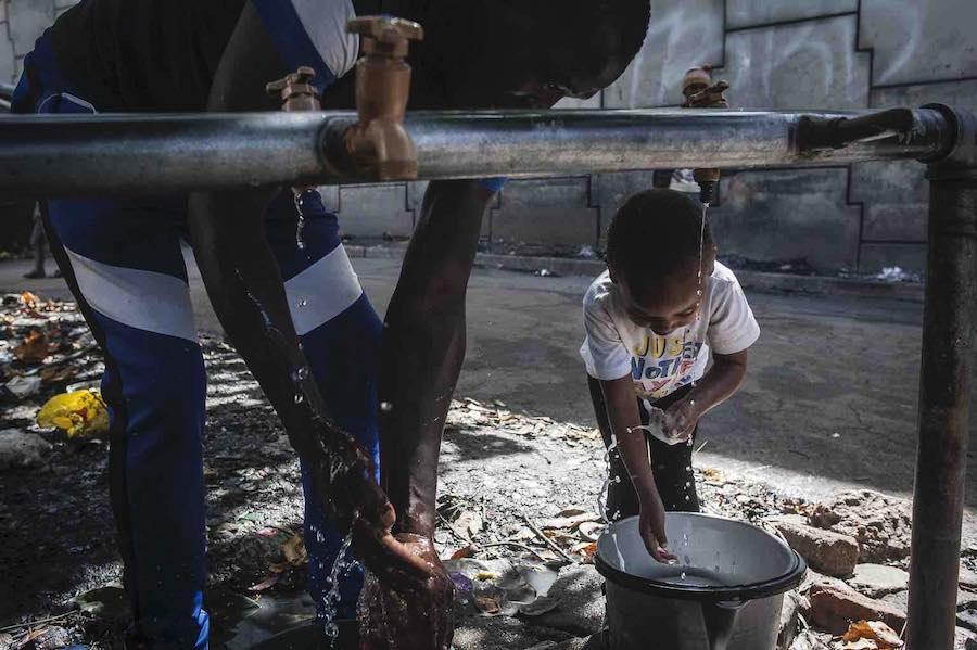 A father and his daughter wash their hands at the informal settlement where they live in Johannesburg, South Africa, where UNICEF is providing water and hygiene supplies to help protect families from the spread of COVID-19. 