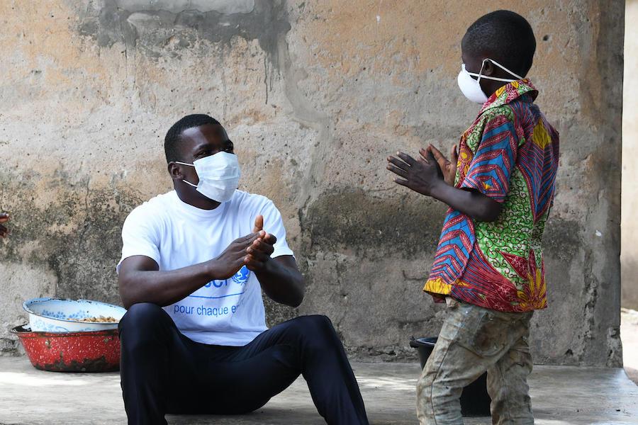  In the village of Morovine, in north Côte d'Ivoire, a UNICEF staff member speaks to a young boy about the importance of washing hands and wearing a face mask to protect against COVID-19. 