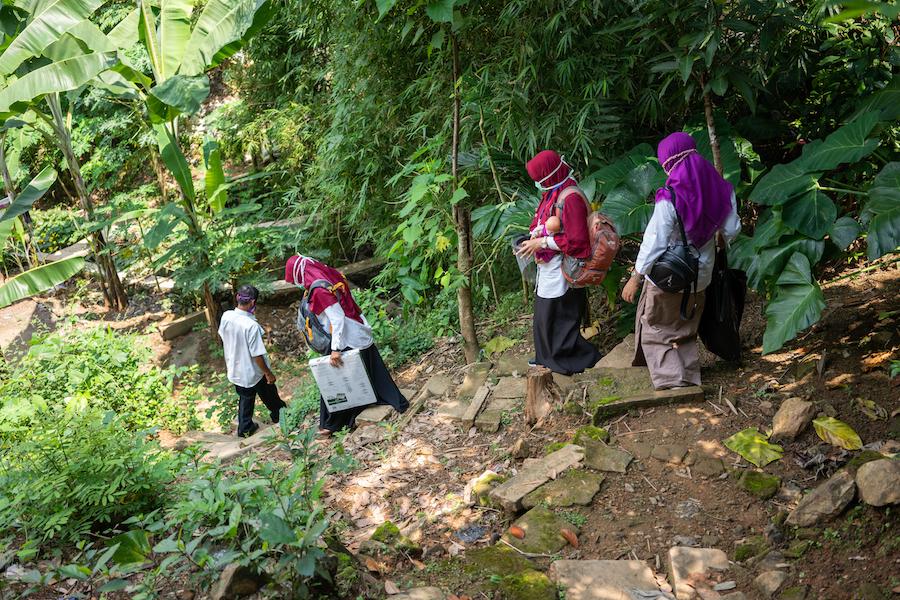 UNICEF-supported nutritionist Dessy Sandra Dewi and colleagues make their way down a steep path to perform home visits to breastfeeding mothers in Paseban Village, Bayat, Klaten, Indonesia.