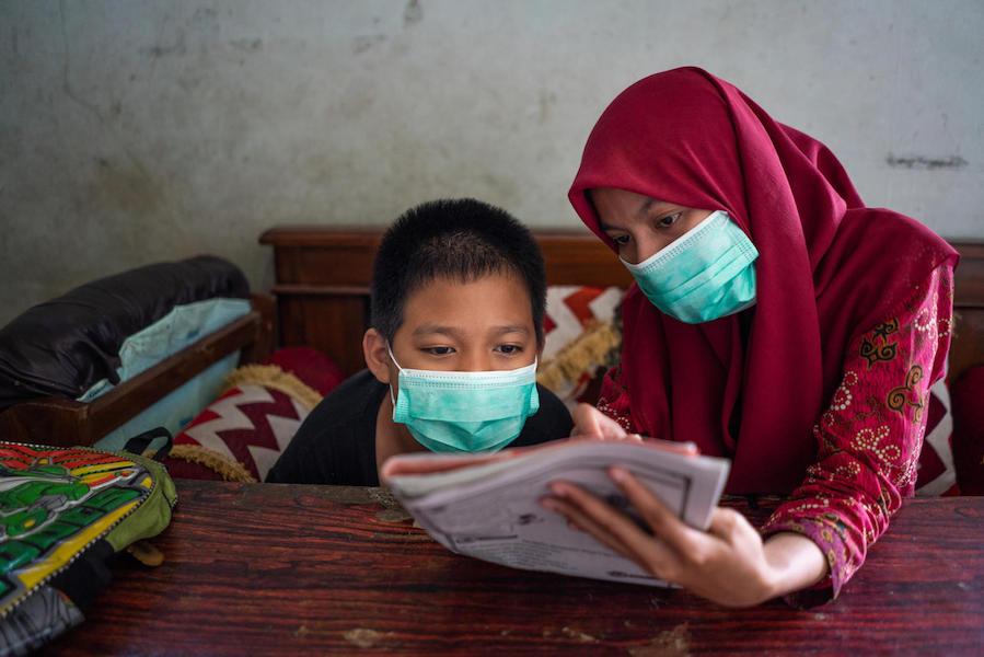 yaiful, 12, a child with a physical impairment, studies with his UNICEF-trained teacher, Fatikhatus, at his grandfather's home in Banyumas, Central Java, Indonesia in 2020..