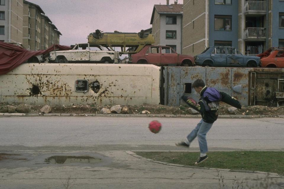 1994-A boy plays soccer on the street in the heavily damaged &quot;front line&quot; suburb of Dobrinja in the besieged capital city of Sarajevo.