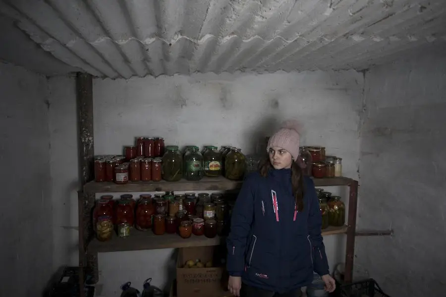 Nastia, 16, checks supplies in the cellar of her family home in eastern Ukraine. Nastia, 16, checks supplies in the cellar of her family home in eastern Ukraine.