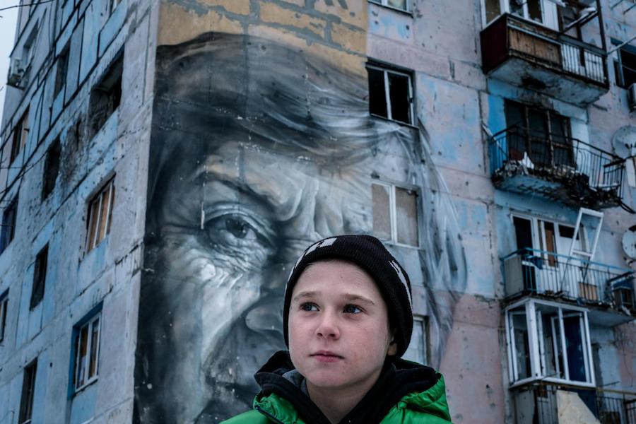 Vadim, 9, stands outside his old home in a building known by locals as the "coloring book," in Avdiivka, Donetsk Oblast, Ukraine. When he was six, he was injured by shelling, and when he was seven, he was run over by a Ukrainian military vehicle.