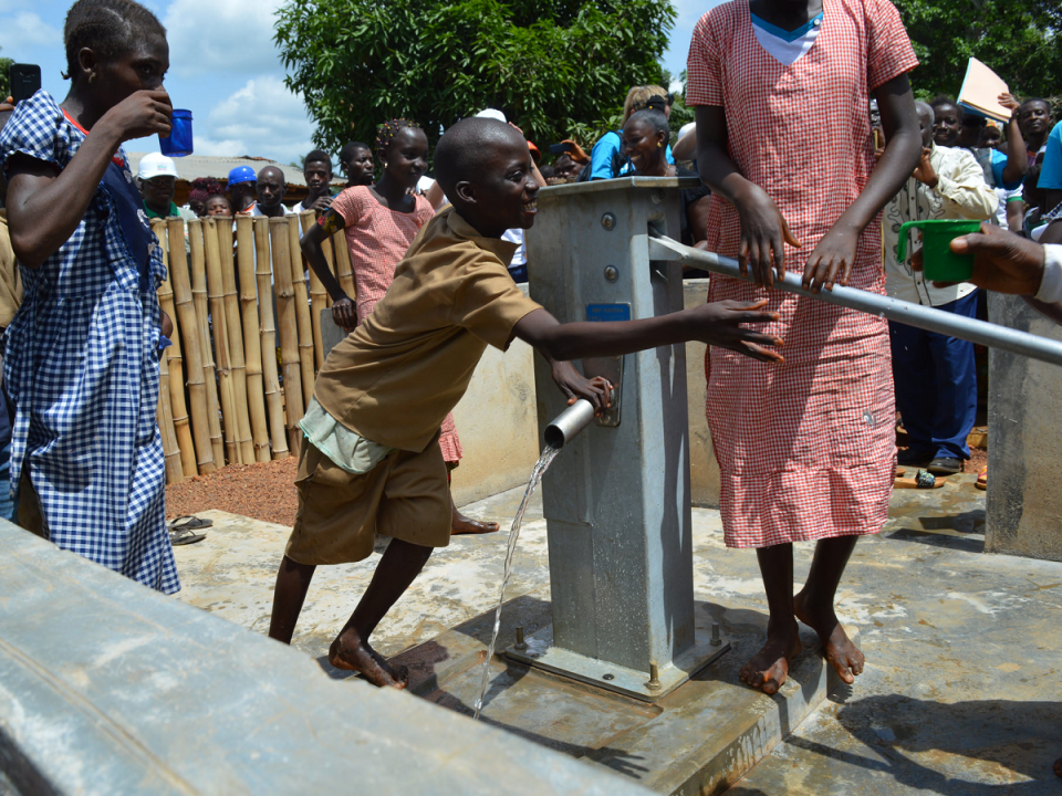 Children in Guinea gather water from a UNICEF-installed water pump in N’Zerekore