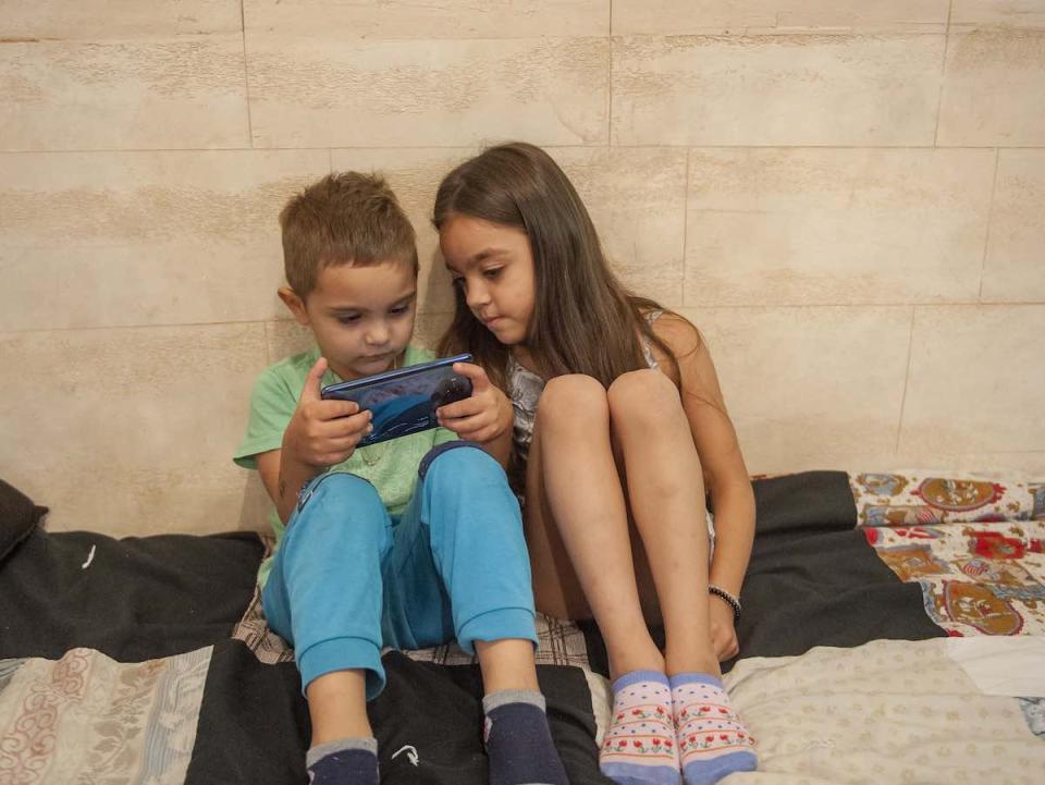 Andrej Madjupaj (4years) and Andjela Madjupaj (6 years) are playing a game on their phone, in their home in Roma settlement in Serbia.