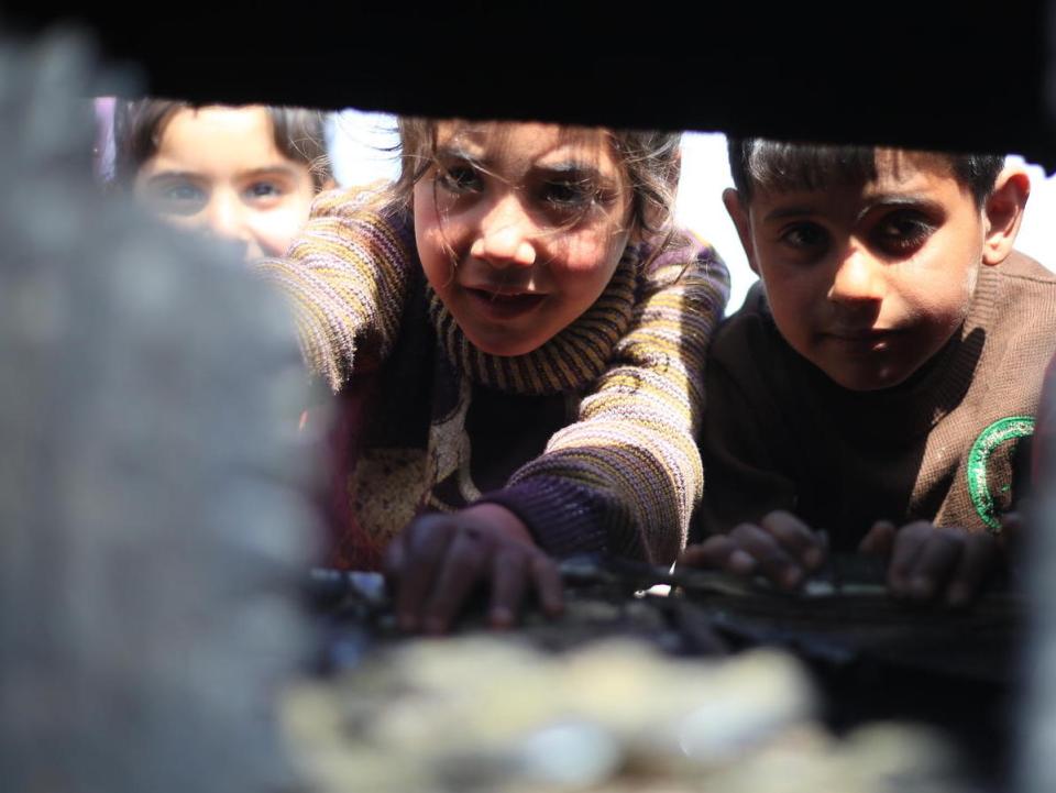 On April 5, 2020, at a tent camp in Idlib in northwestern Syria, children sift through the wreckage left when their family’s tent caught fire from a gas stove. 