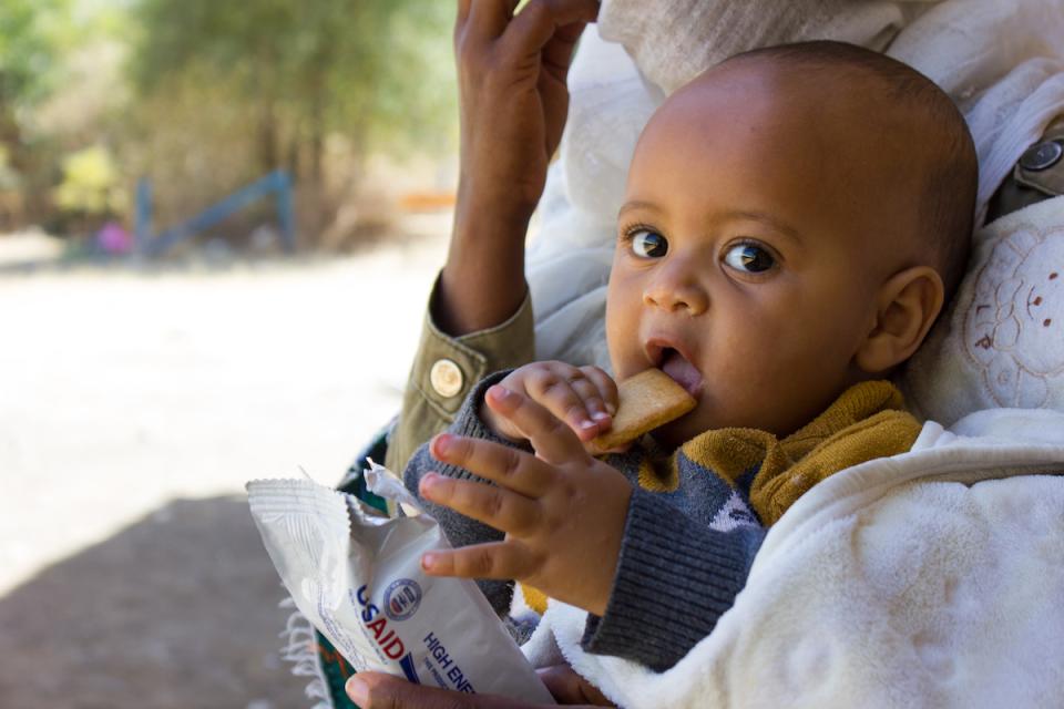 An infant eats a nutritional biscuit supplied by UNICEF as part of ongoing relief efforts for children and families displaced by violence in Ethiopia's Tigray region.