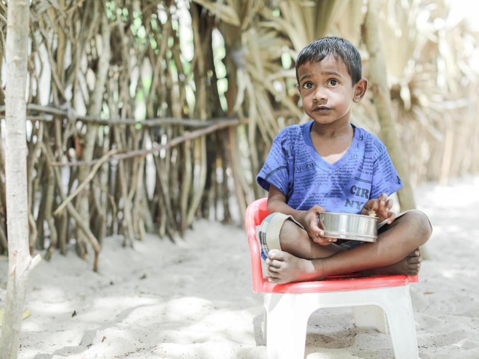 On July 5, 2022, 5-year-old Thulakshan eats his meal while sitting outside his house in the village of Devapuram, Batticaloa, Sri Lanka. 