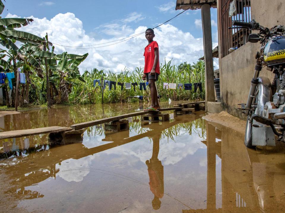 Peretimfa, 11, stands on a makeshift wooden walkway over floodwaters outside his home in Sagbama, Bayelsa State, Nigeria. 